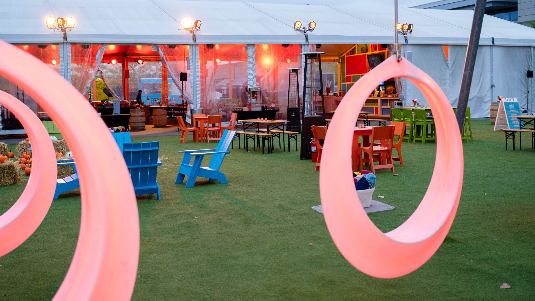 A pink swing is hanging from a tree in a park.