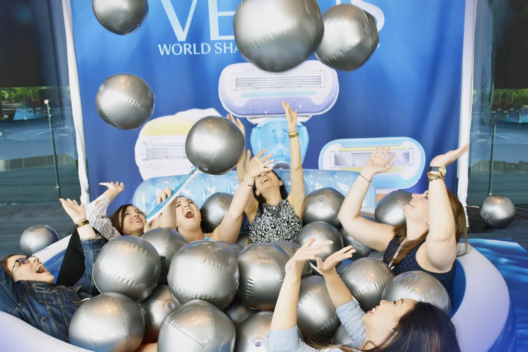 A group of women are playing in a pool of silver balls.