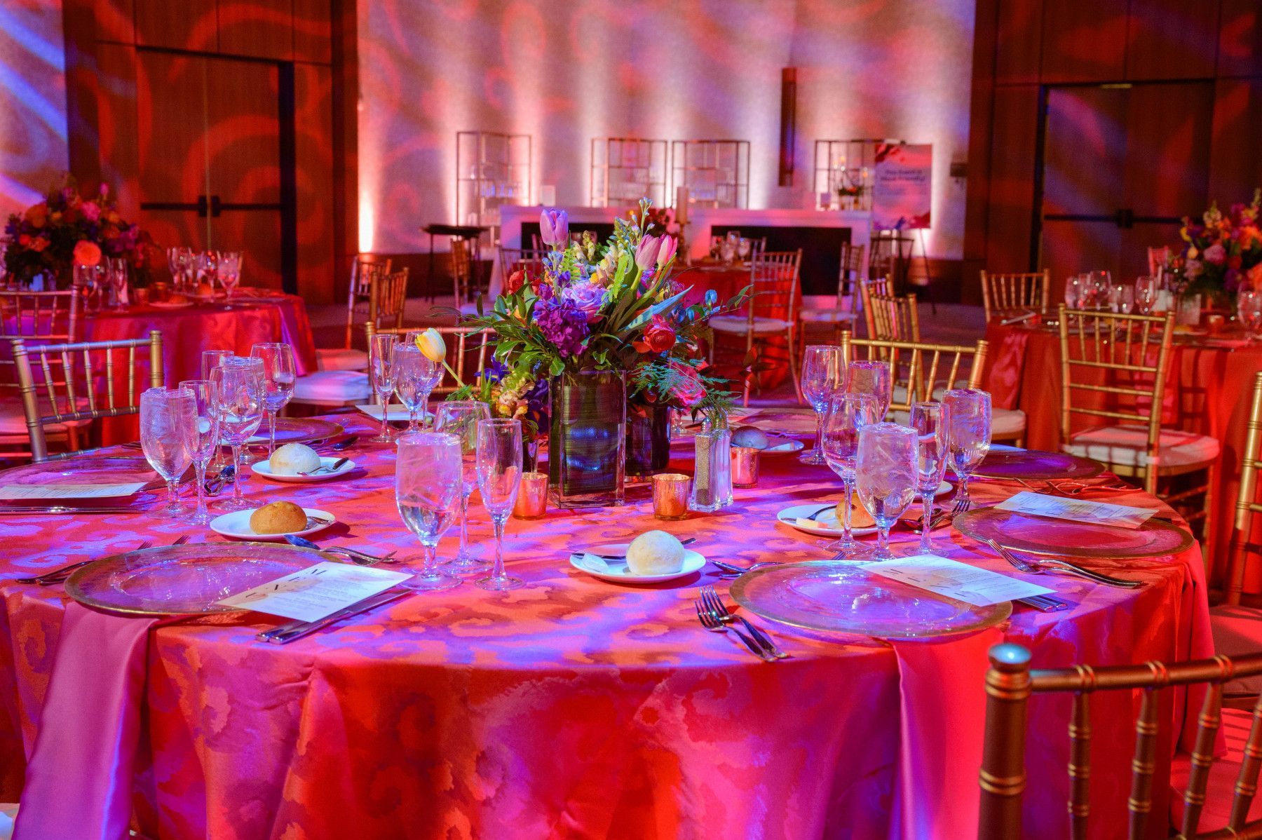 A table set for a wedding reception with pink tables and chairs.