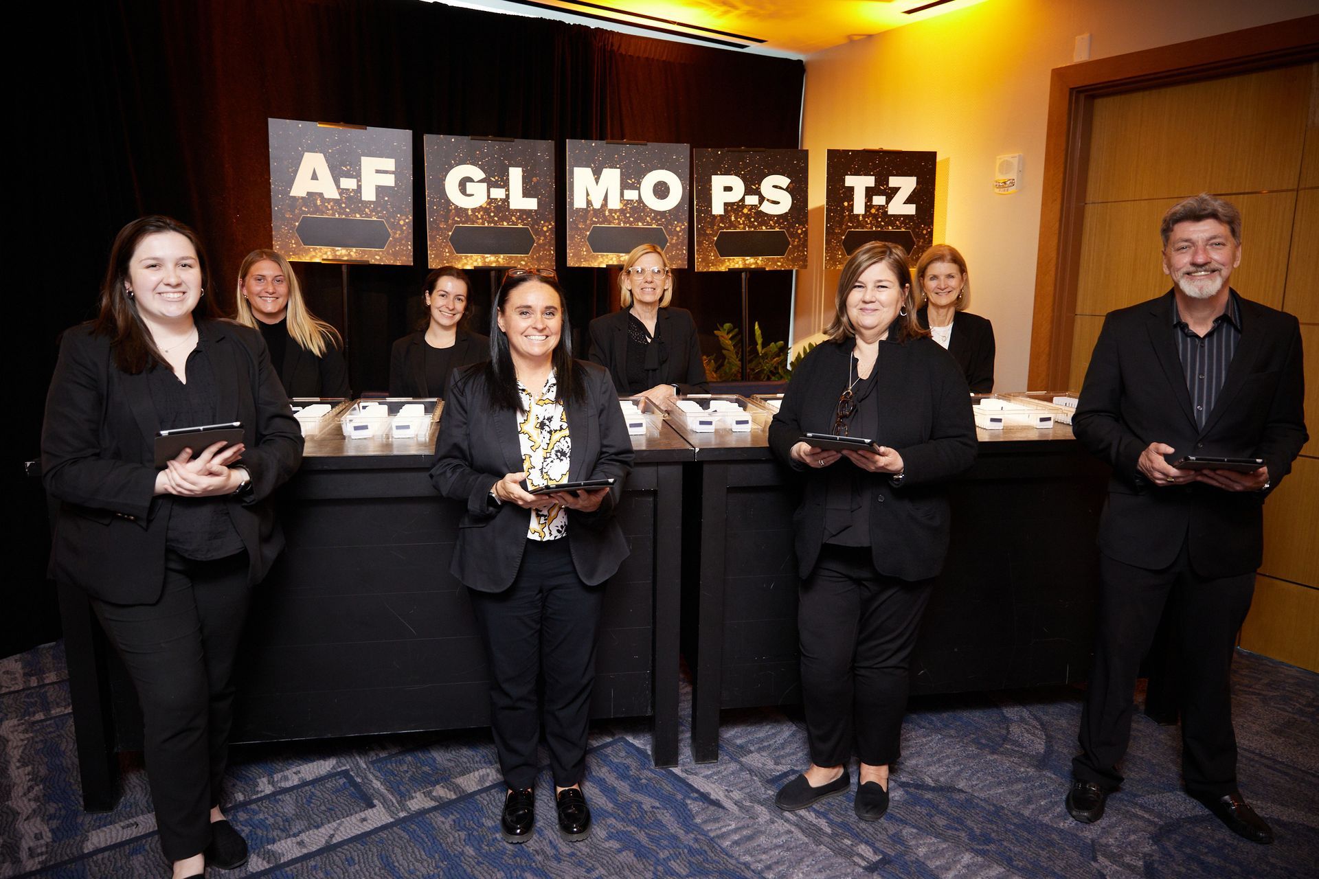 A group of people standing in front of a counter with signs that say a-f g-l mo p-s t-z