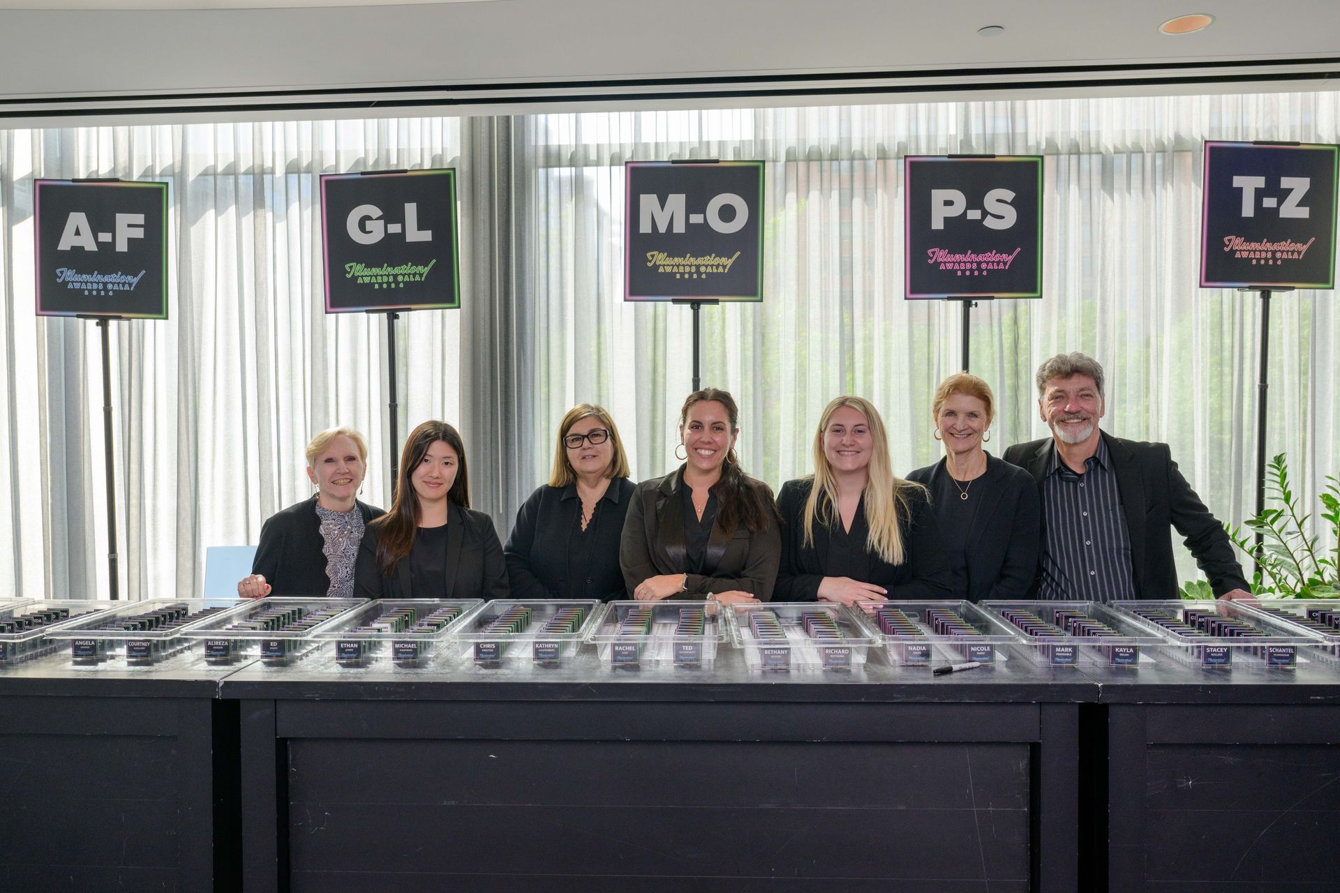 People at a reception desk with letter signs above them.