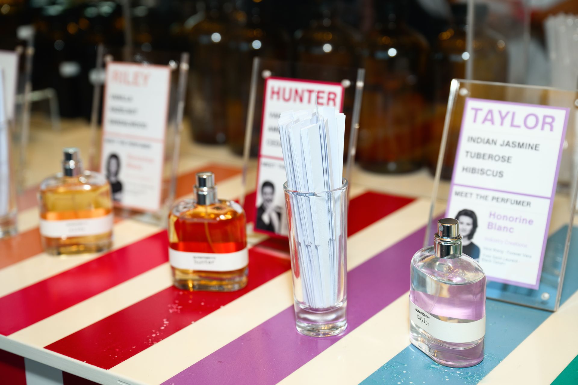 Fragrance bottles on striped table runners with name signs, including Hunter and Taylor.