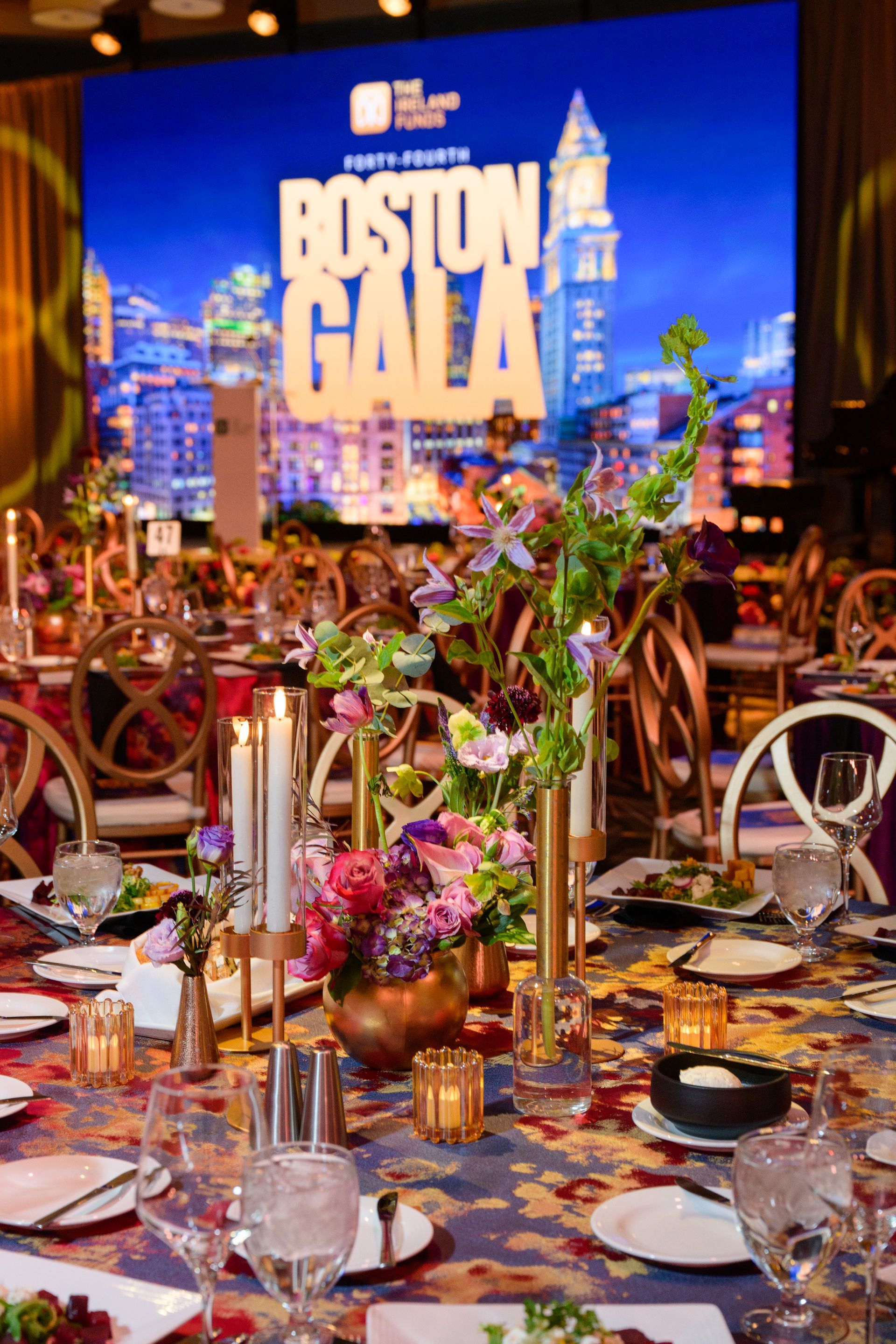Elegant gala table setting with floral centerpiece, candles, and Boston Gala backdrop.