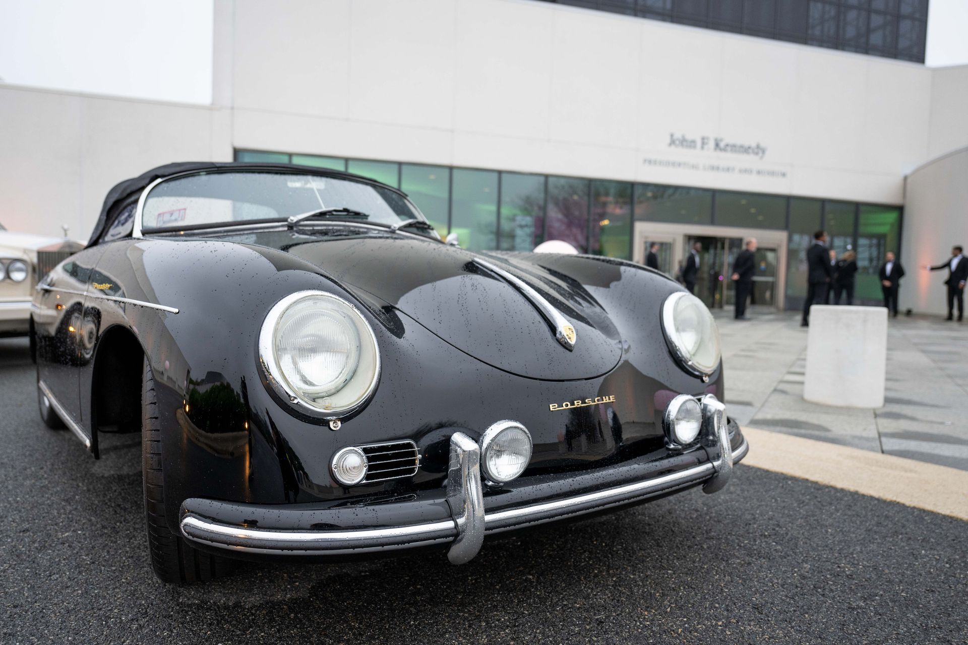 Black vintage Porsche convertible parked in front of the John F. Kennedy Presidential Library and Museum.