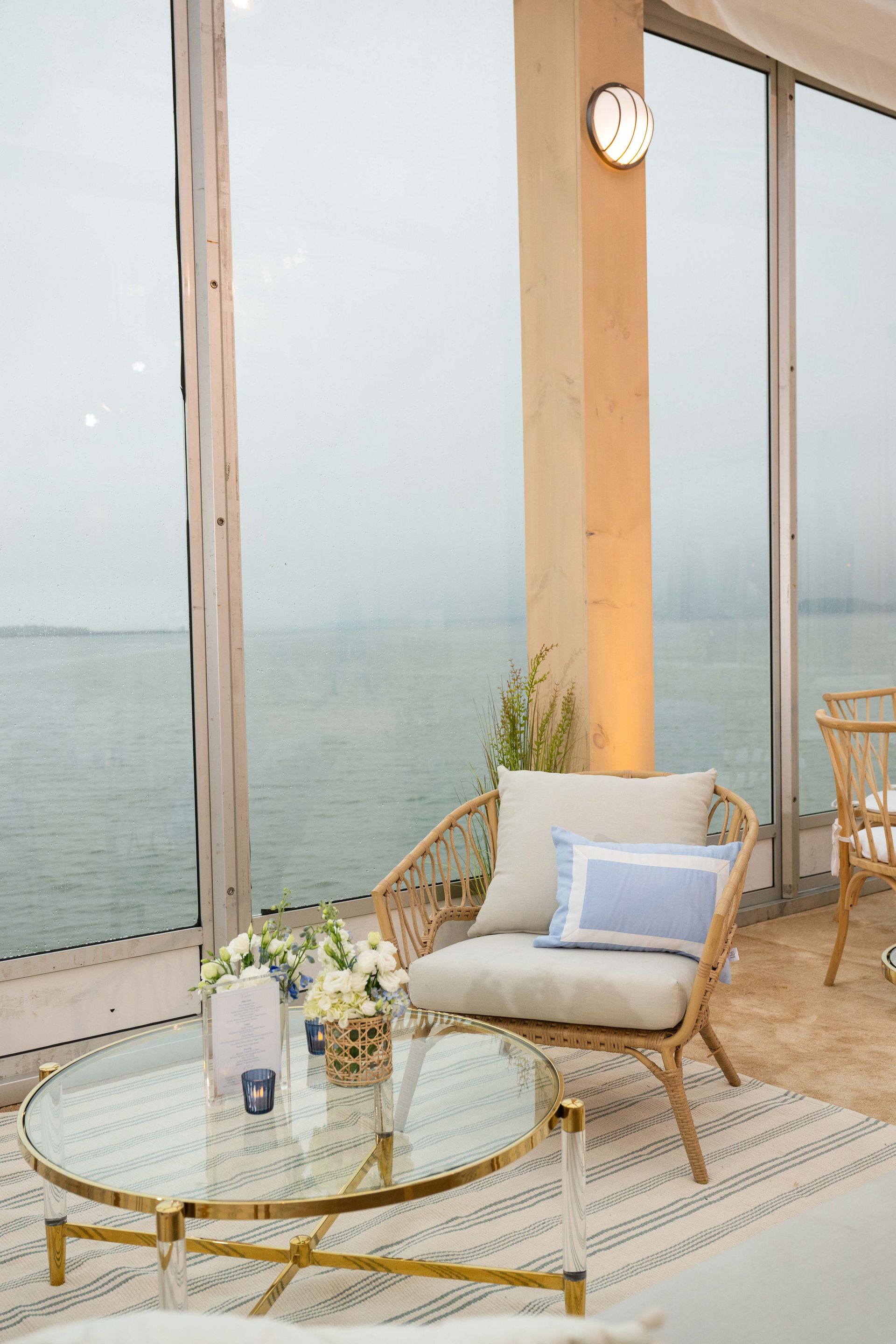 Wicker chair and glass table with flowers, overlooking a misty ocean view.
