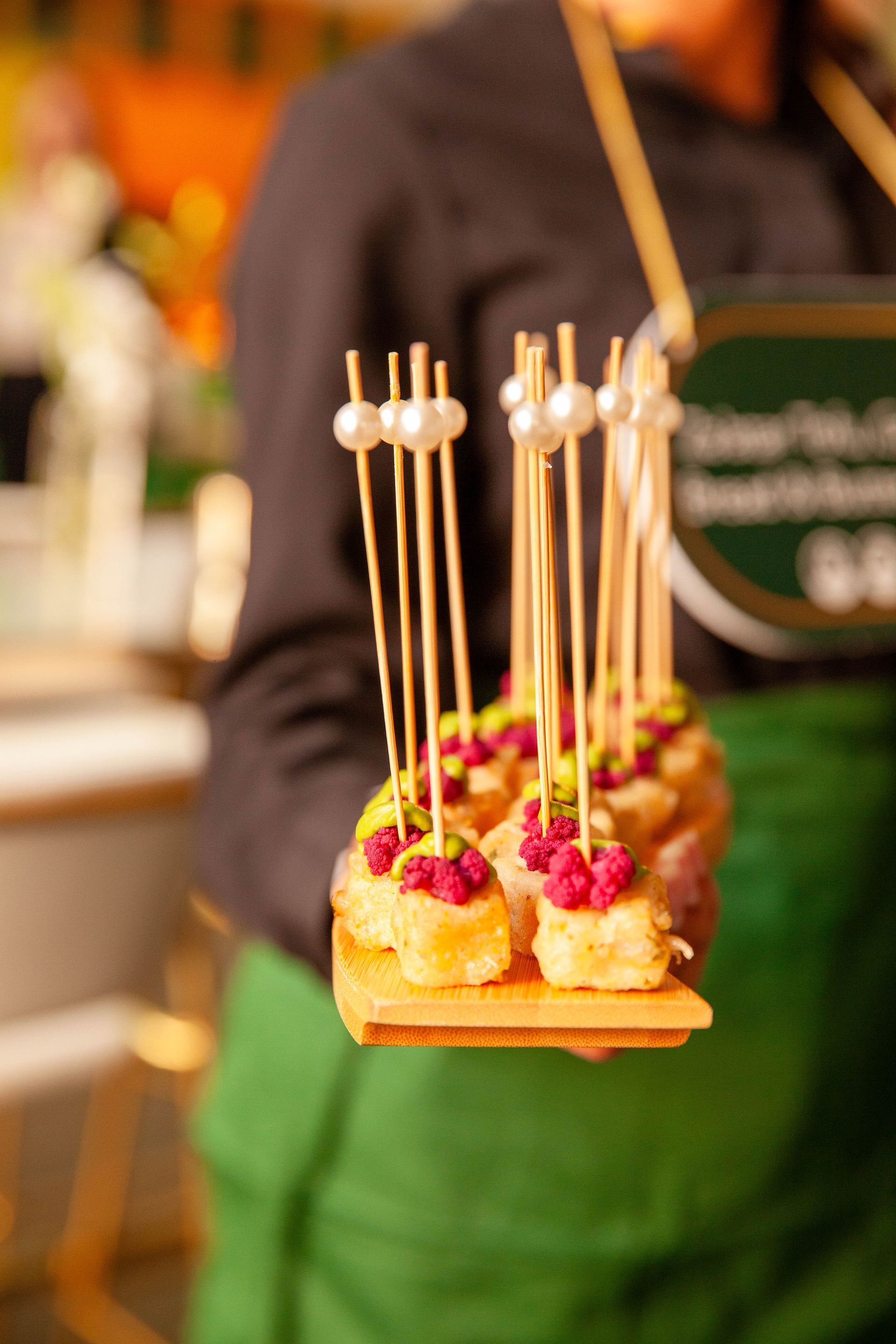 Person holding tray of appetizers with decorative pearl skewers.