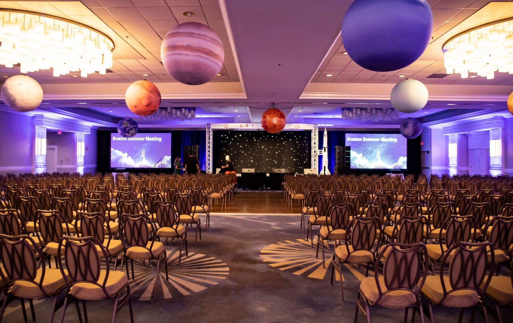A large room with rows of chairs and balloons hanging from the ceiling.