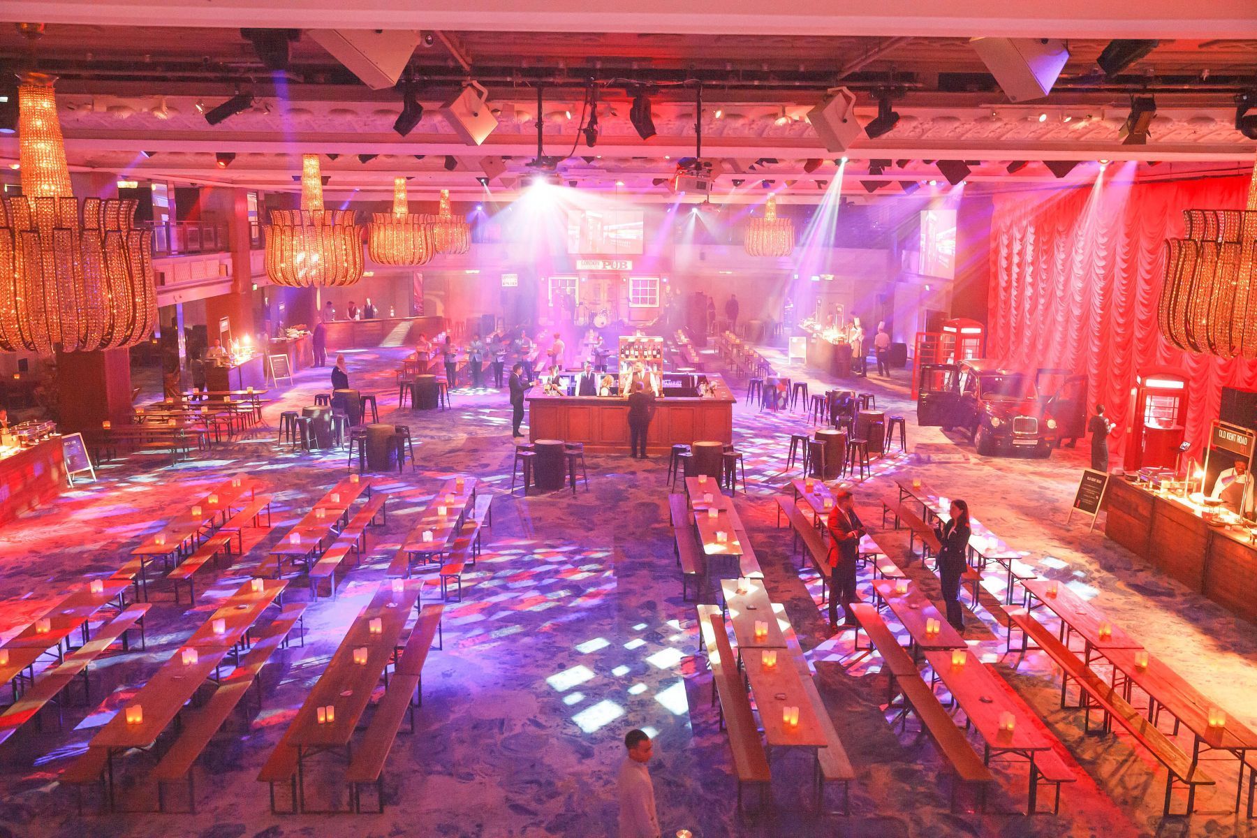 A large room filled with tables and benches and purple lights.