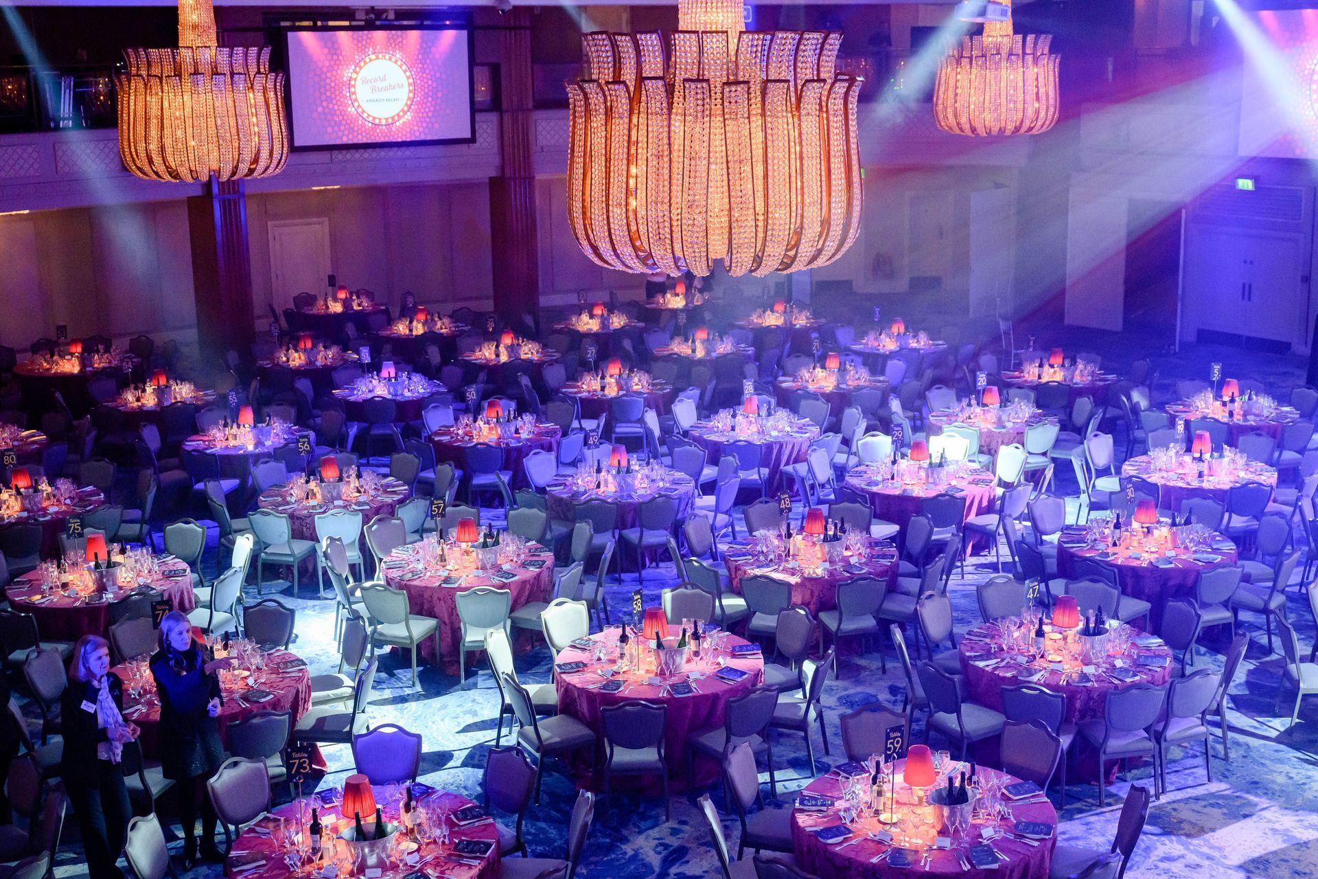 A large room filled with tables and chairs and a chandelier.