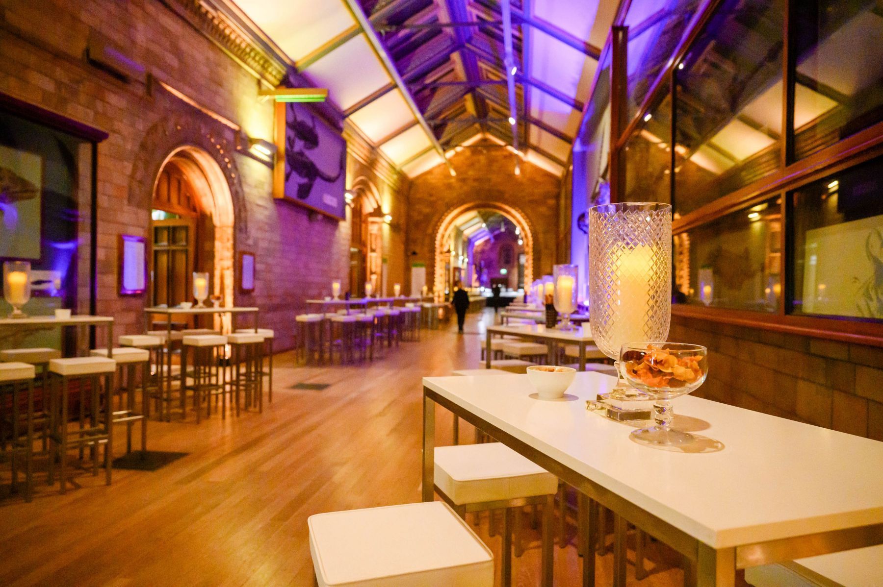 A large room with tables and stools and purple lights.