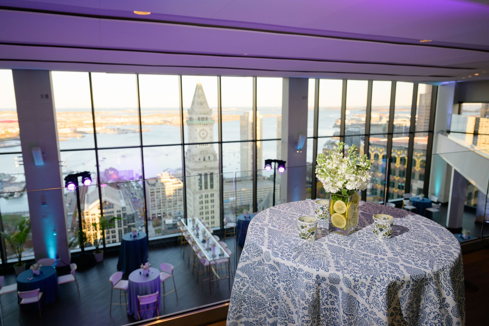 Party venue with city views; table with floral arrangement, blue and purple decor.