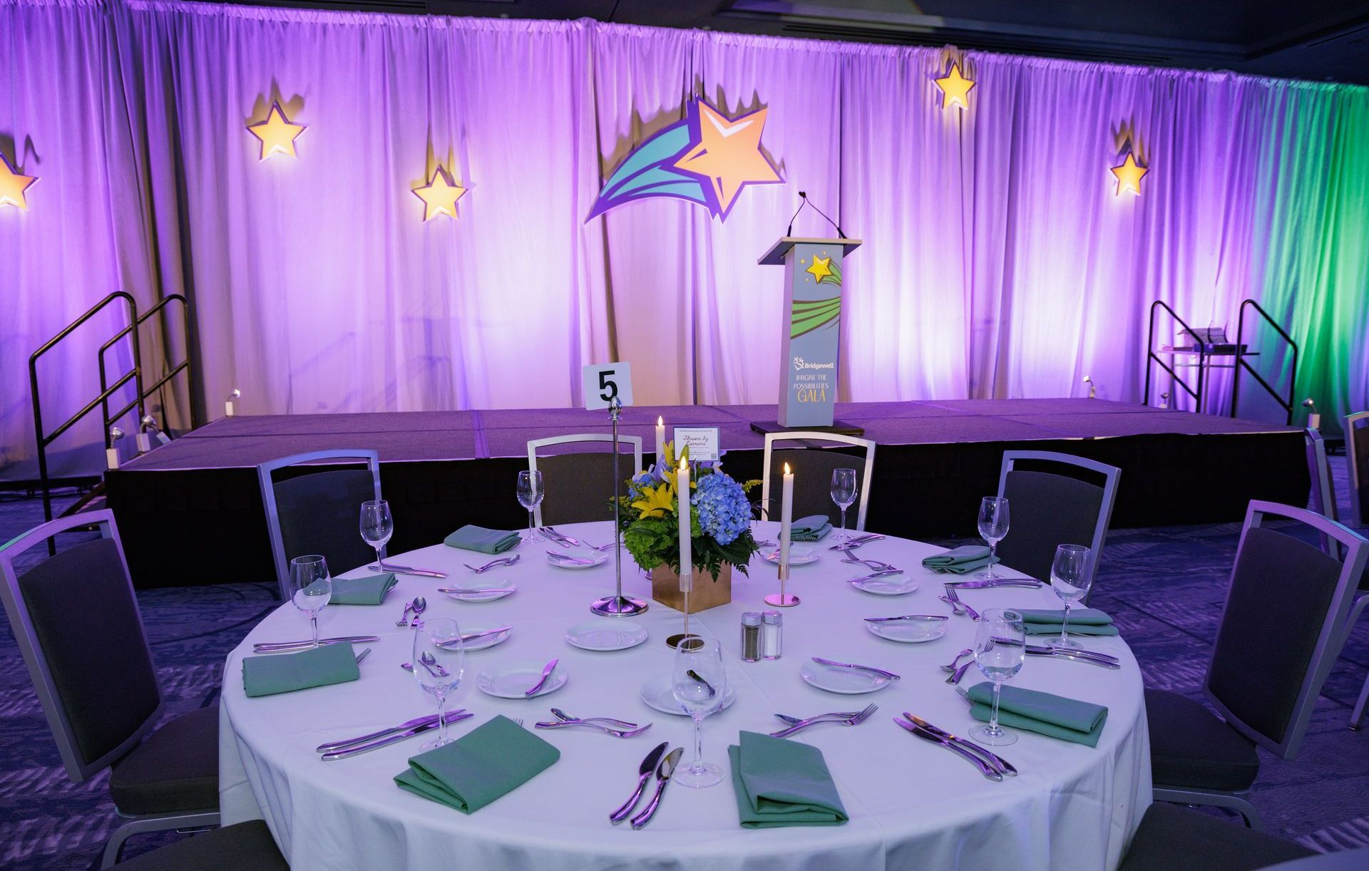 A round table is set for a dinner party in front of a stage.