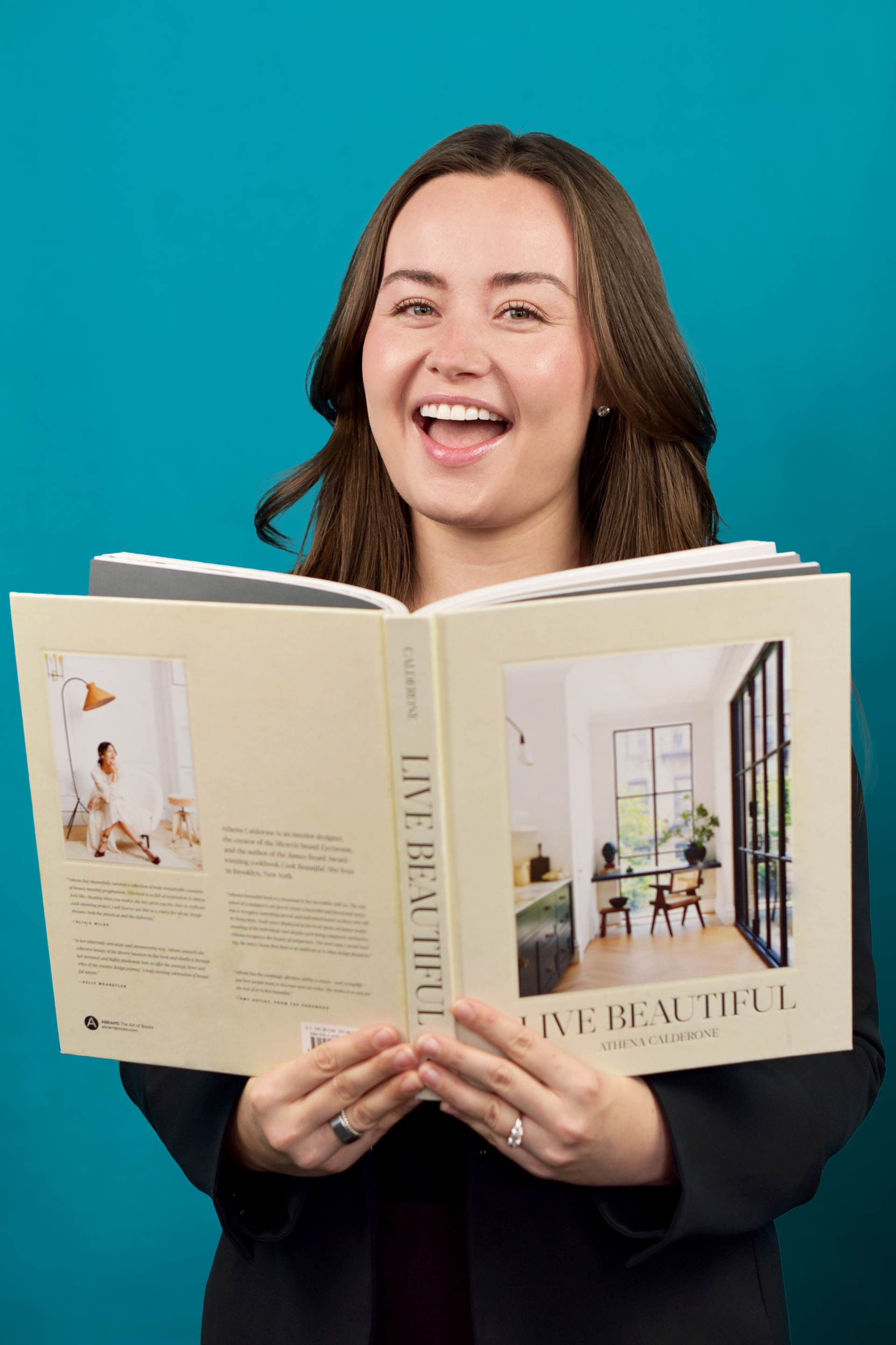 A woman in a pink dress is holding a cupcake with butterflies on it.