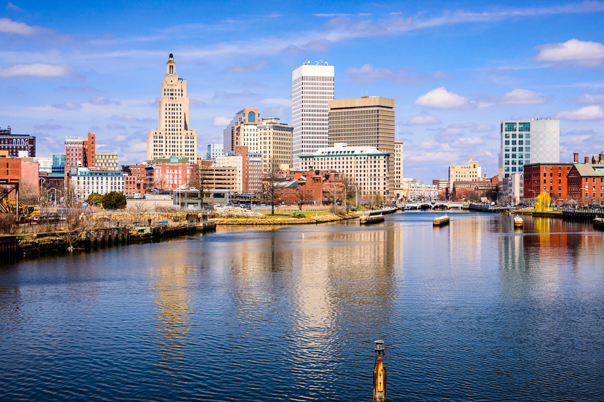 A city skyline is reflected in the water of a river.