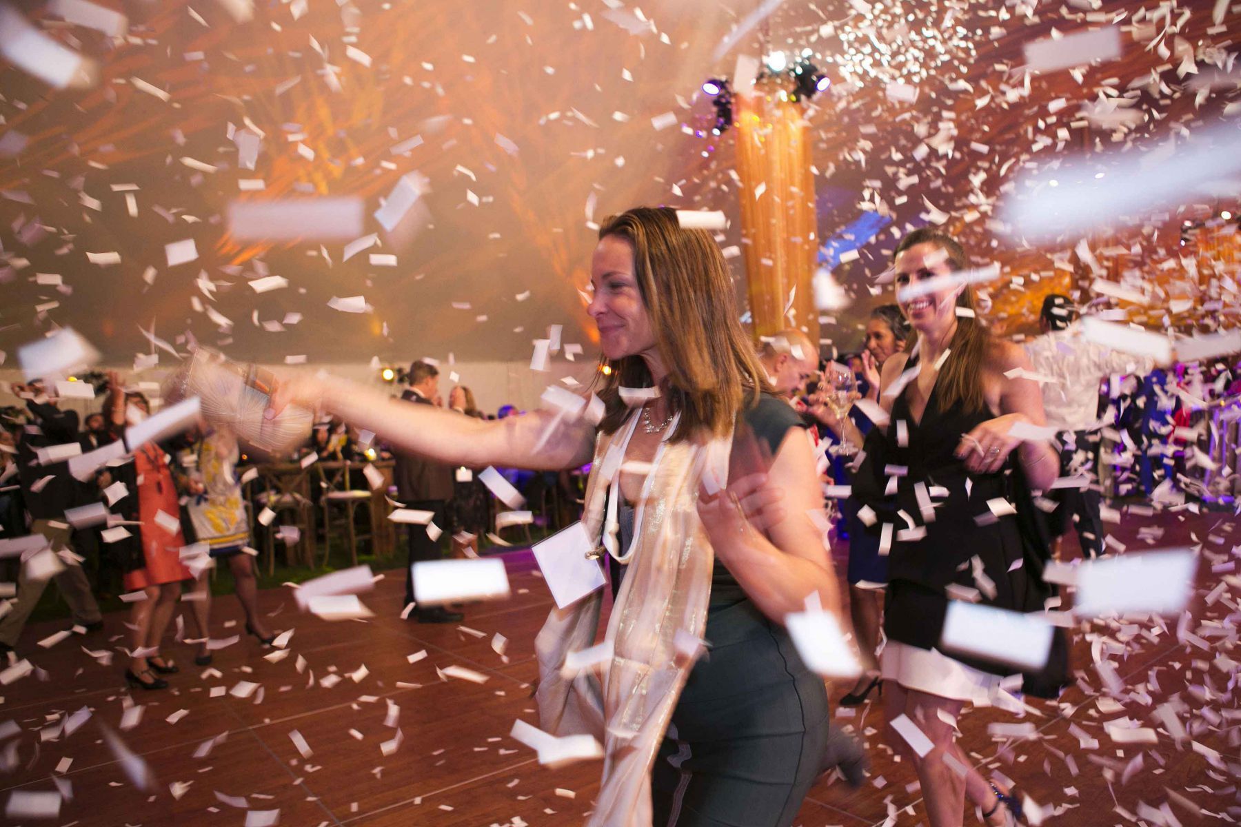 A woman is dancing in a room with confetti falling around her.