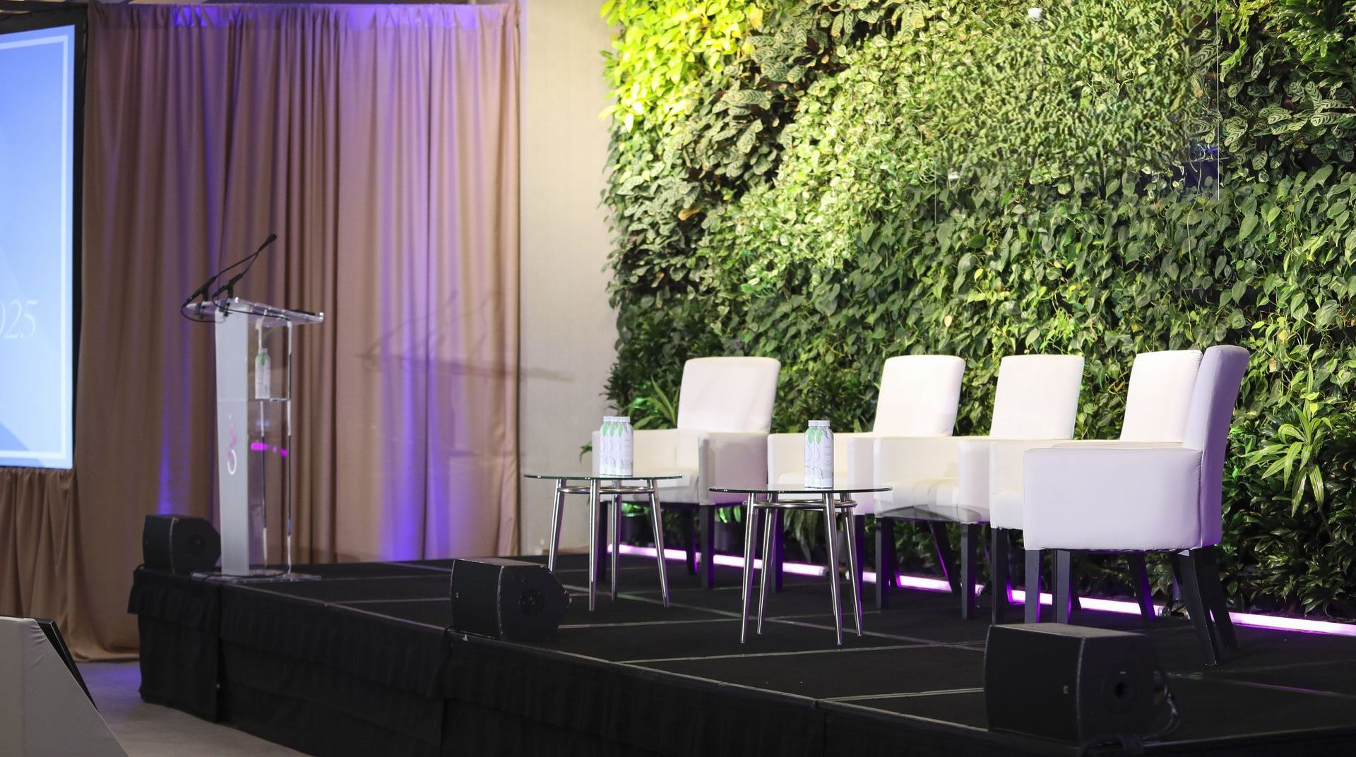 A stage with chairs and a podium in front of a green wall.