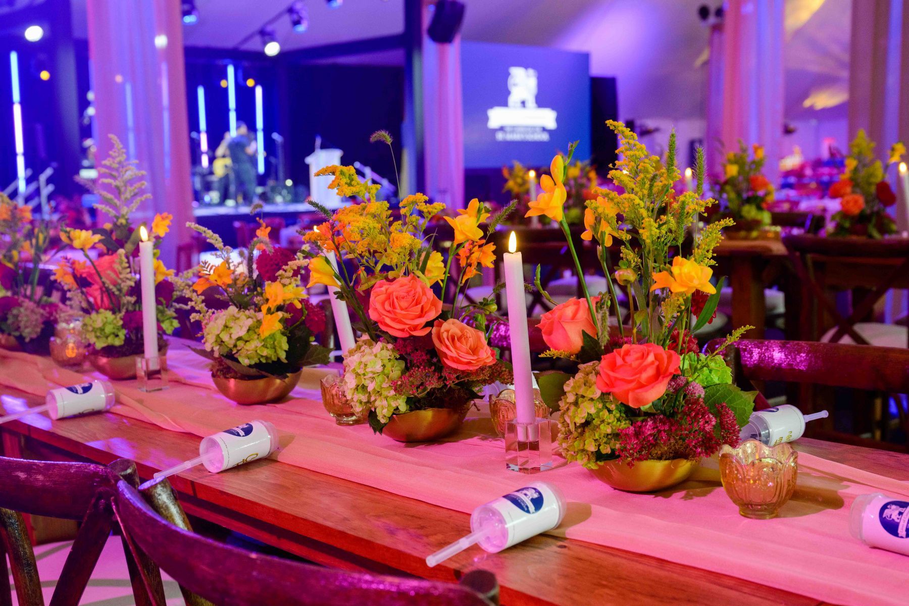A long table with flowers and candles on it.