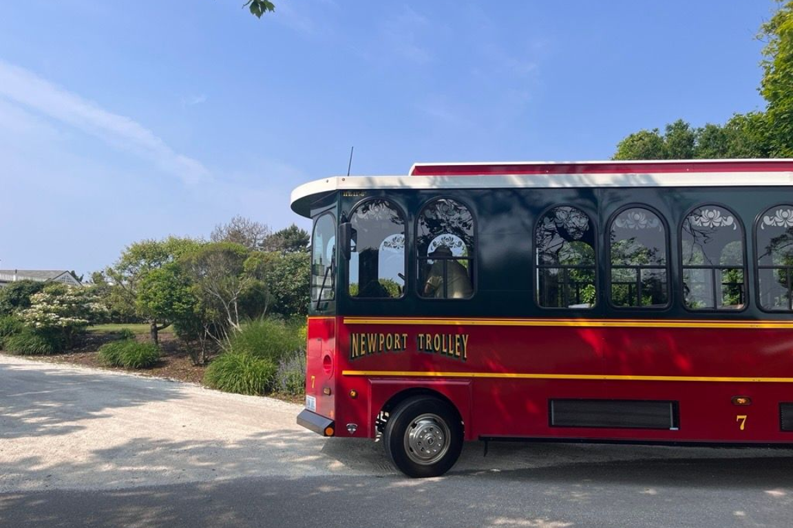 Two men seated at a panel discussion on a stage. One speaks, the other holds papers. Blue backdrop and floral arrangement.