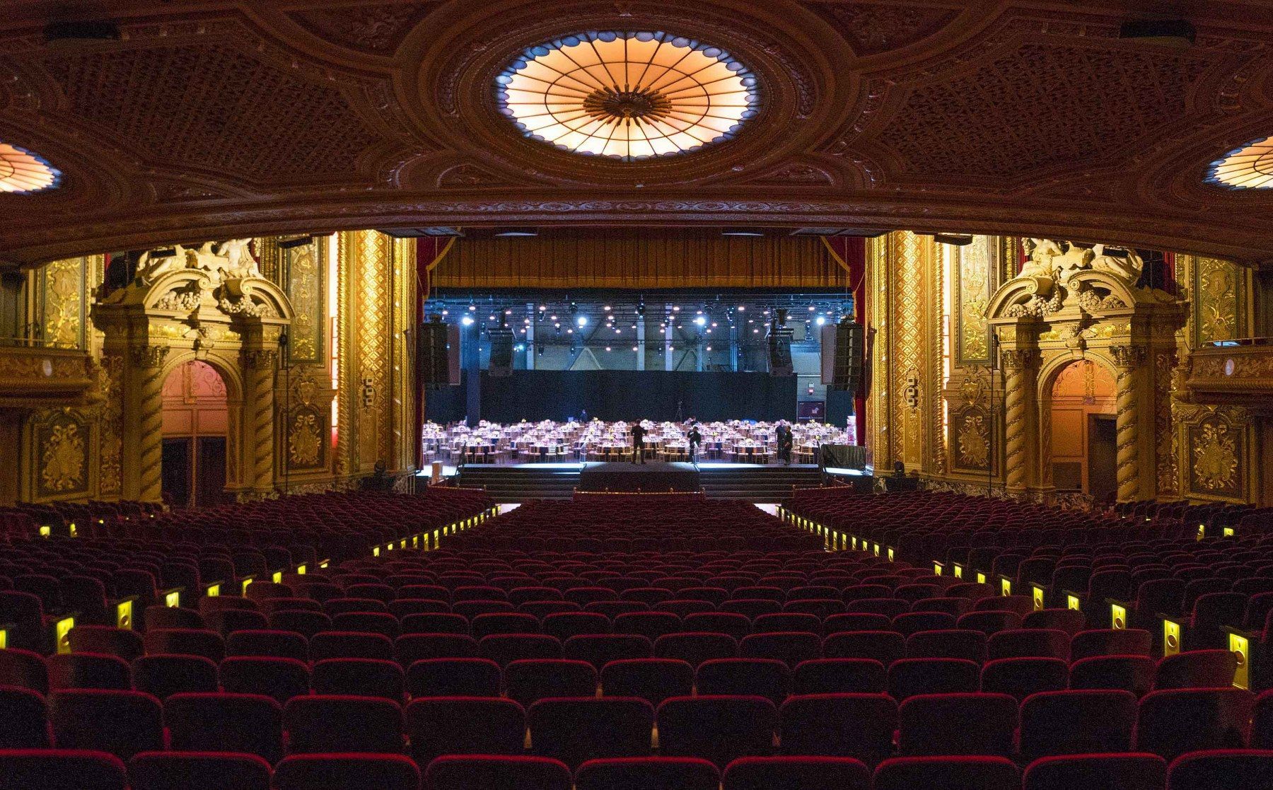 An empty auditorium with red seats and a stage in the background