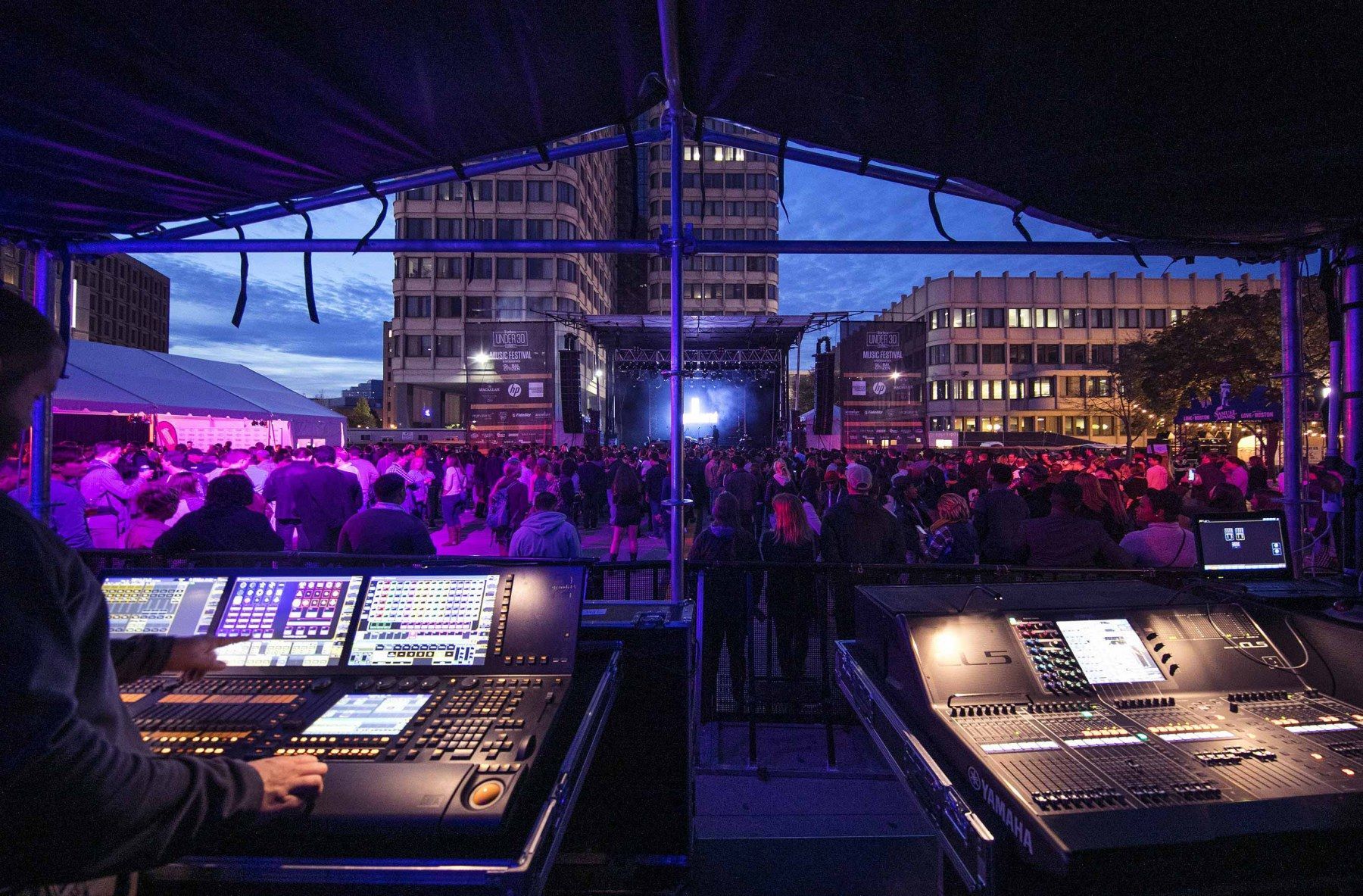 A crowd of people are gathered under a canopy at a concert