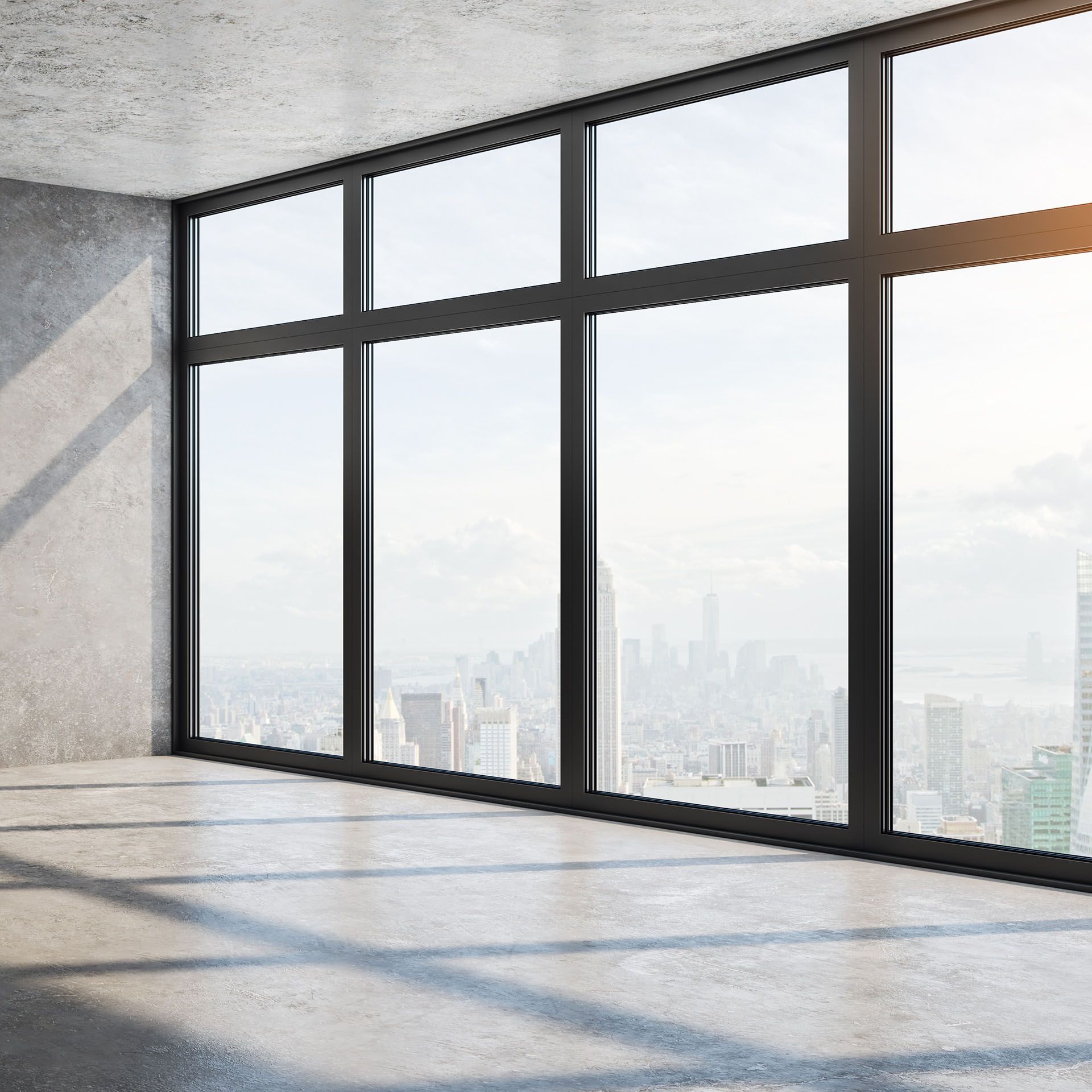 An empty room with a lot of windows and a view of the city.