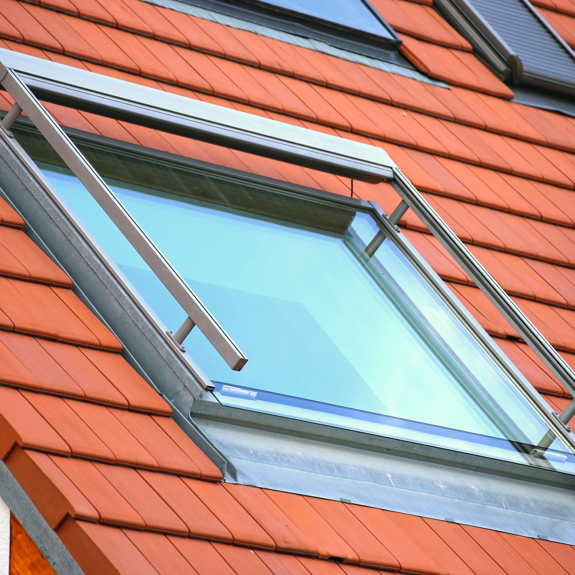 A roof window on a red tiled roof.