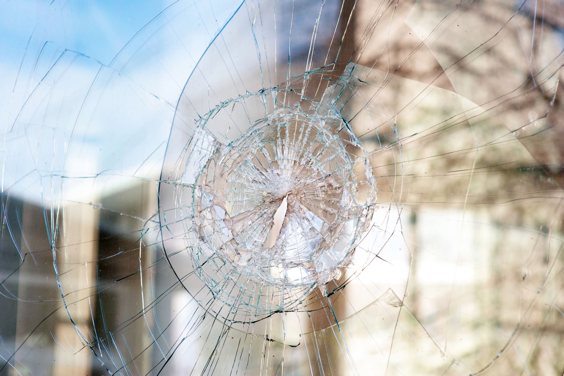 A close-up of a broken glass window with a hole in it.