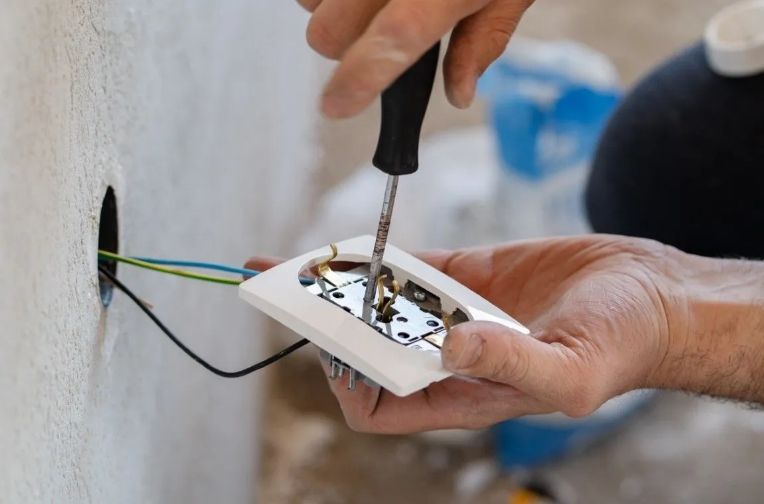 Electrician installing a wall outlet.