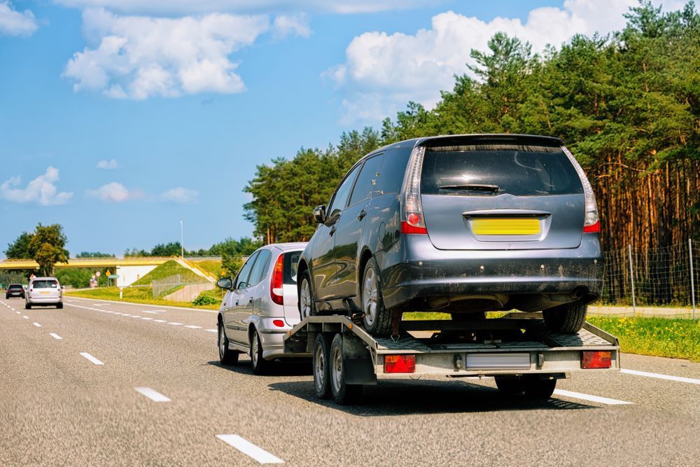 A Car Is Being Towed by A Tow Truck on A Highway — Mahers Smash Repairs in Wauchope, NSW