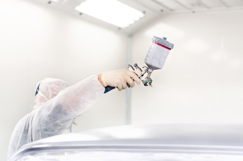 A Man Is Painting a Car — Mahers Smash Repairs in Nundle, NSW