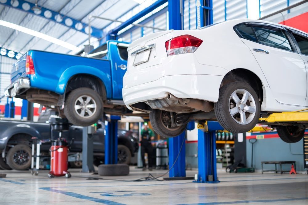Two Cars Are Sitting on A Lift in A Garage — Mahers Smash Repairs in Walcha, NSW