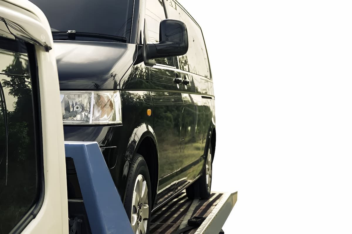 A Black Van Is Being Towed By A Tow Truck — Mahers Smash Repairs in Tamworth, NSW