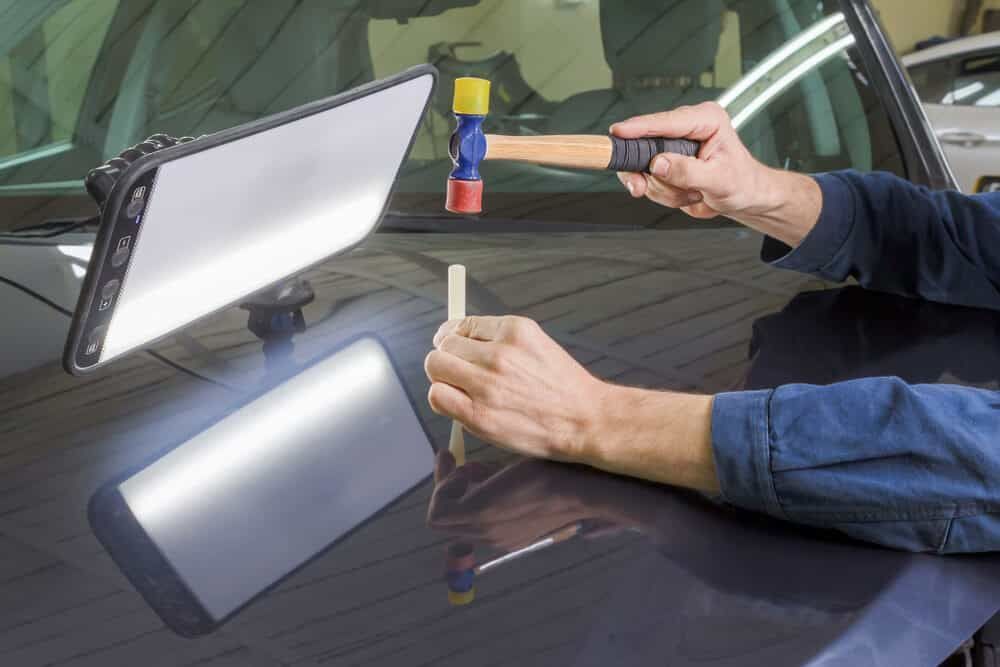A Person Is Using A Hammer To Fix A Dent On A Car — Mahers Smash Repairs In Manilla, NSW