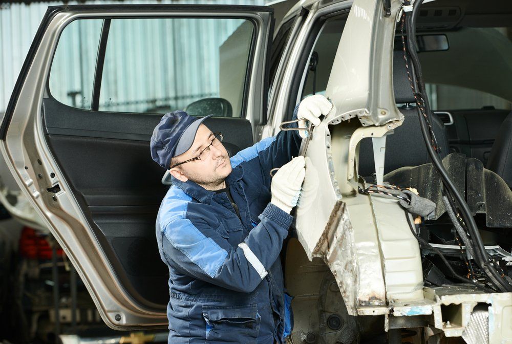 A man is working on the back of a car in a garage-Experience Mechanic in Canberra