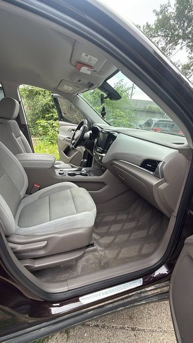 Open car door showing light gray interior seats and dashboard from the driver’s side
