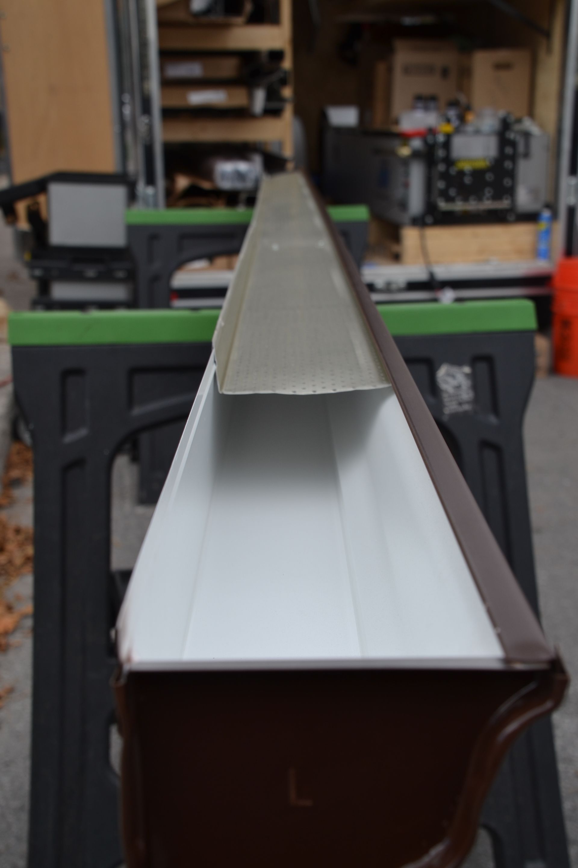 Une gouttière brune et blanche, visible à l'intérieur et à l'extérieur, est posée sur un établi.