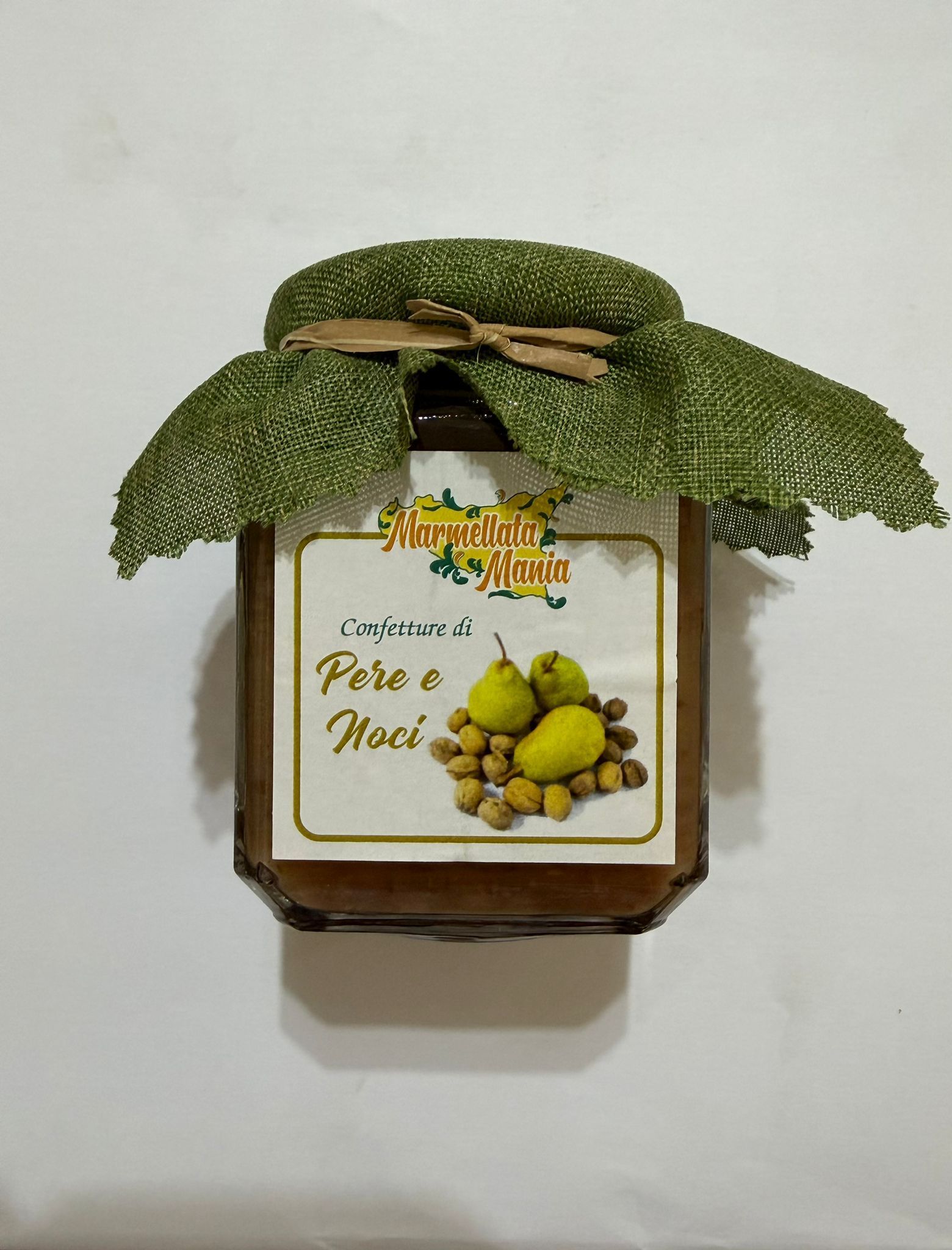 Piccola scatola regalo decorativa con fiocco a forma di foglia verde ed etichetta a forma di pera su sfondo bianco.