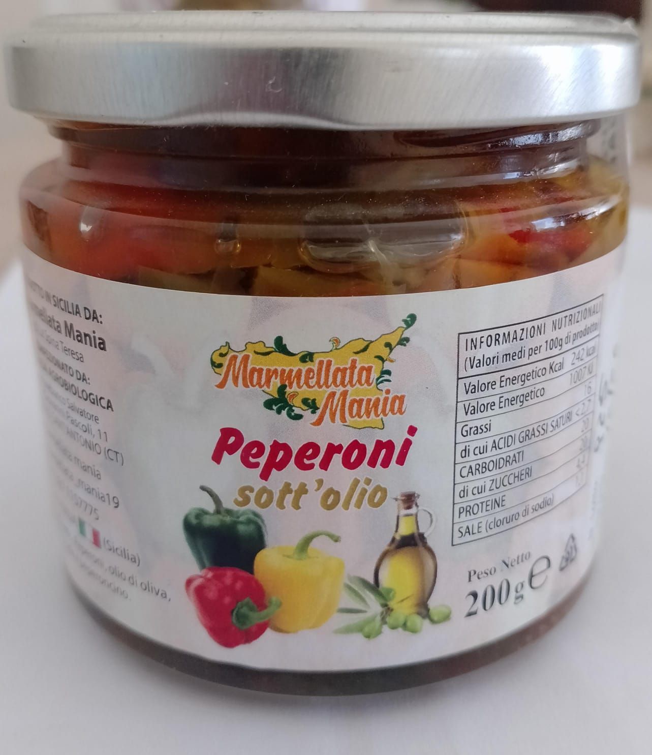 Barattolo di peperoni rossi marinati in olio con coperchio argentato ed etichetta colorata su sfondo bianco.