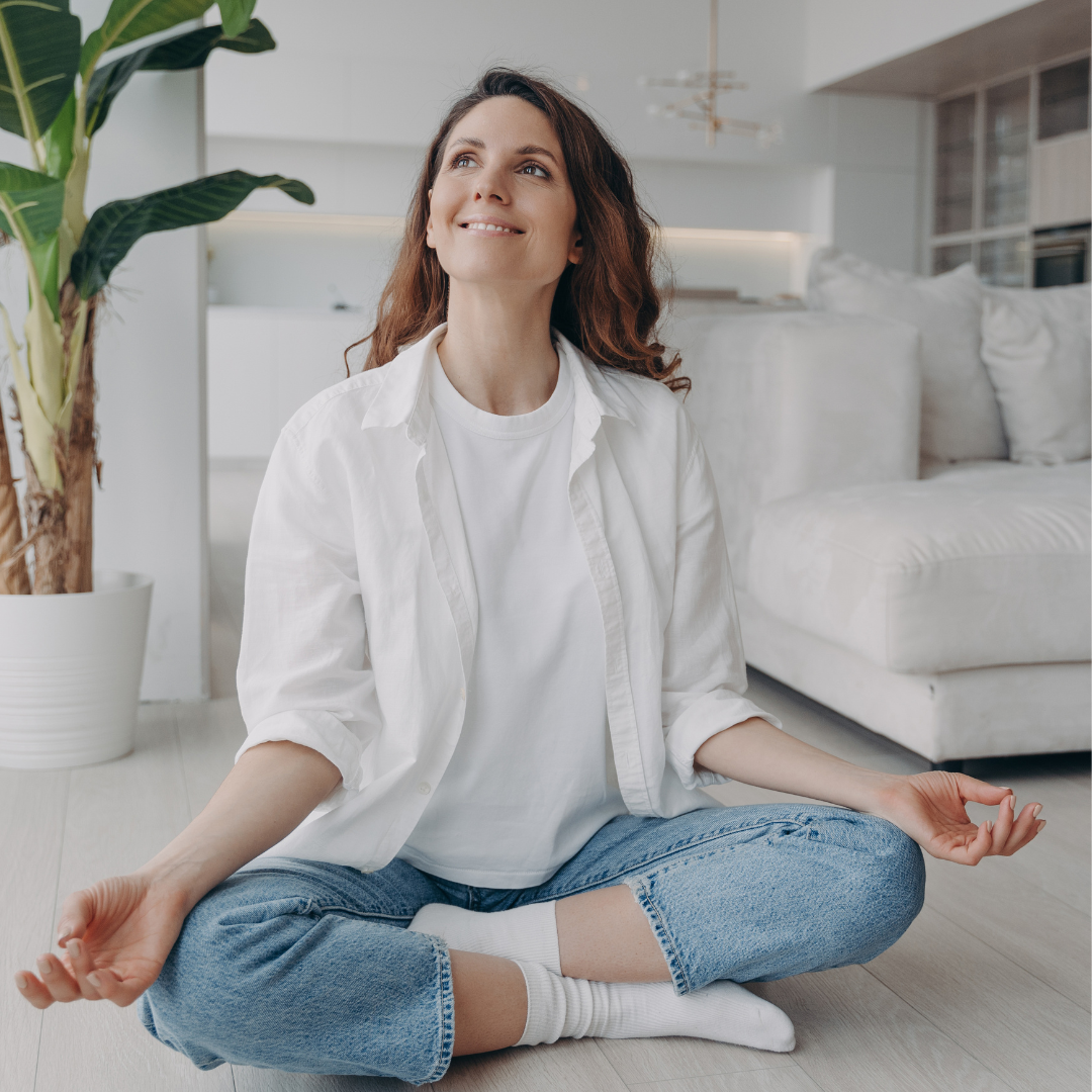 A woman is sitting on the floor in a lotus position.
