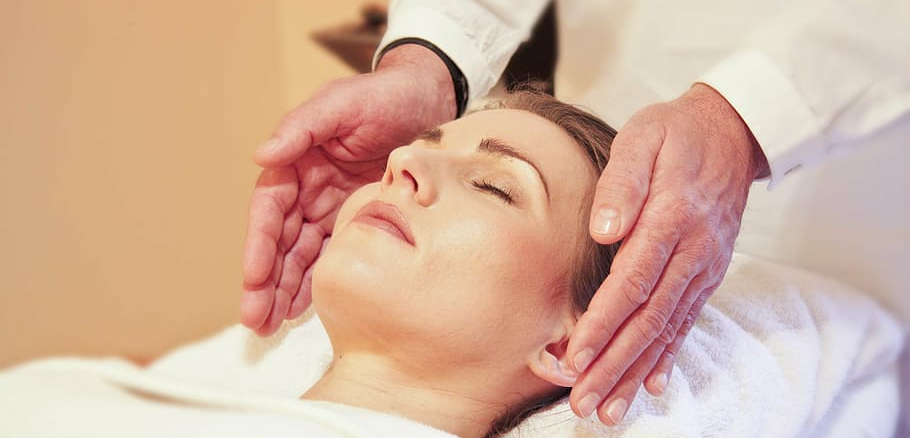 A woman is getting a facial massage at a spa.