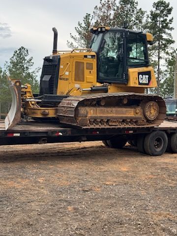 Yellow CAT bulldozer on a flatbed trailer in an outdoor setting.