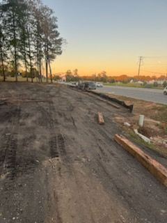 Dirt road next to a highway, trees in the background, dusk sky.