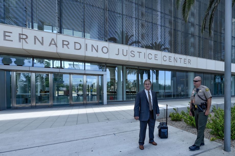 Left, Gregory Kassel defense attorney in this photo, two men are standing in front of a building that says 'San Bernardino Justice Center.