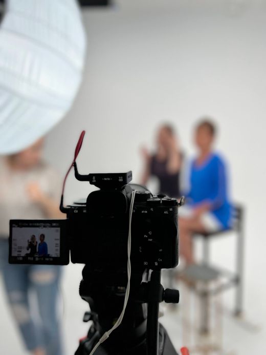 Camera filming two blurred people in a bright studio setting