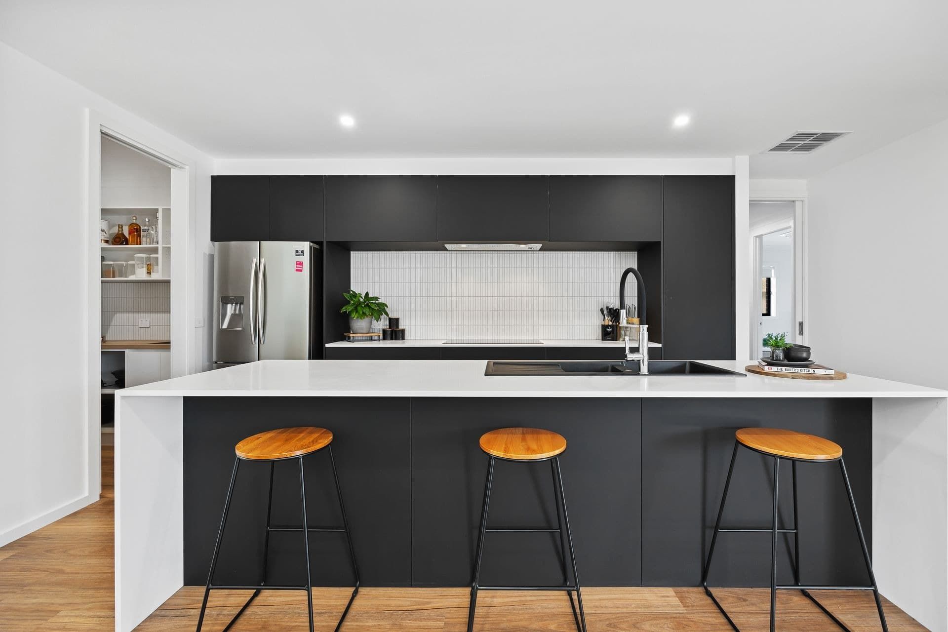 A Kitchen With Black Cabinets and White Counter Tops and Stools — Jetsonian Constructions In Wendouree, VIC