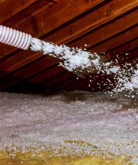 A white hose is spraying white foam into a room