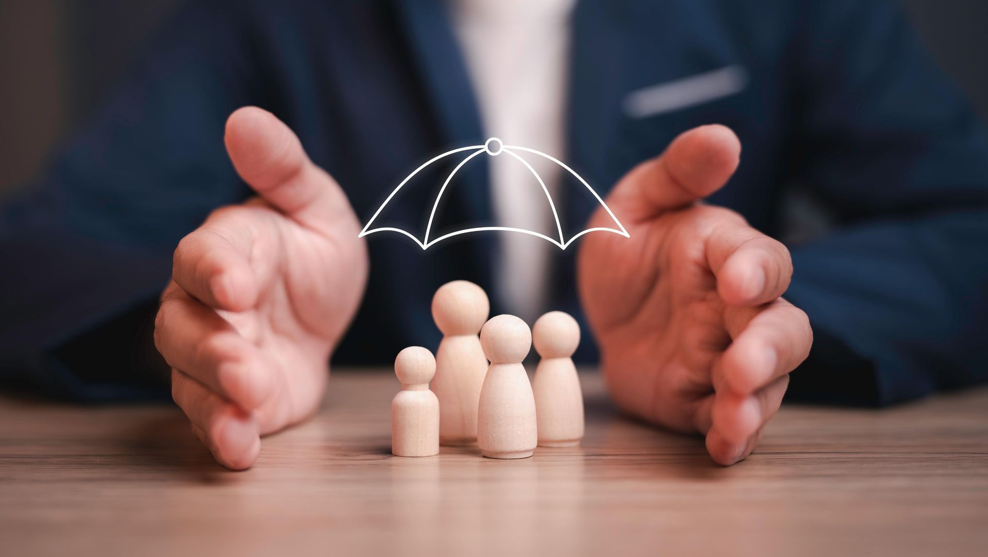 Person's hands protecting wooden family figures under an umbrella symbol, representing family insurance.