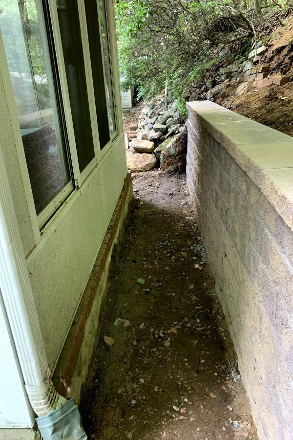 A sidewalk leading to a house with a brick wall.