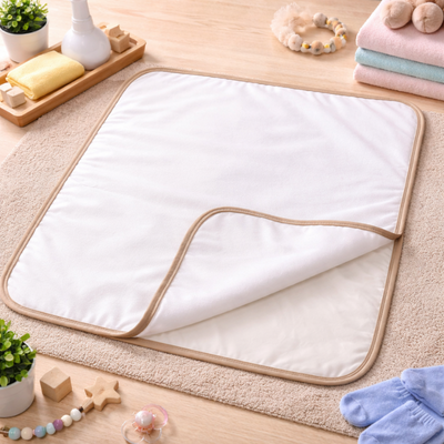 Cambiador de bebé blanco con ribete marrón sobre una alfombra, rodeado de artículos para bebés.