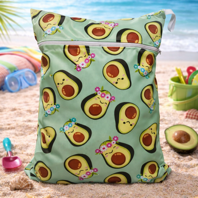 Bolso verde con estampado de aguacate en una playa de arena.